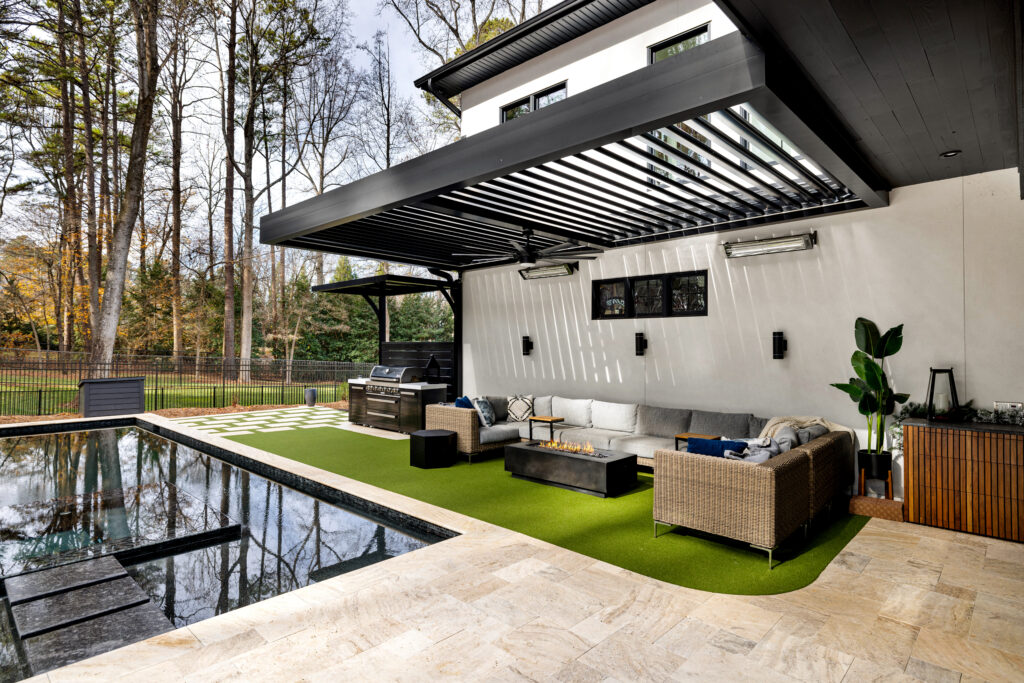 Luxury backyard with motorized louvered pergola, poolside lounge seating, fire pit table, and outdoor kitchen grill area