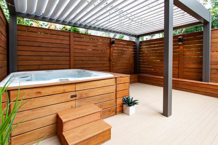 Modern hot tub patio in Colorado featuring a motorized louvered pergola, cedar privacy walls, composite decking, and luxury outdoor living design.