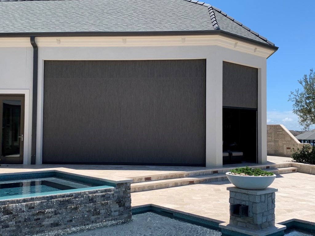 Modern luxury Colorado home with MagnaTrack motorized patio screens enclosing an outdoor living area beside a custom pool and stone patio.